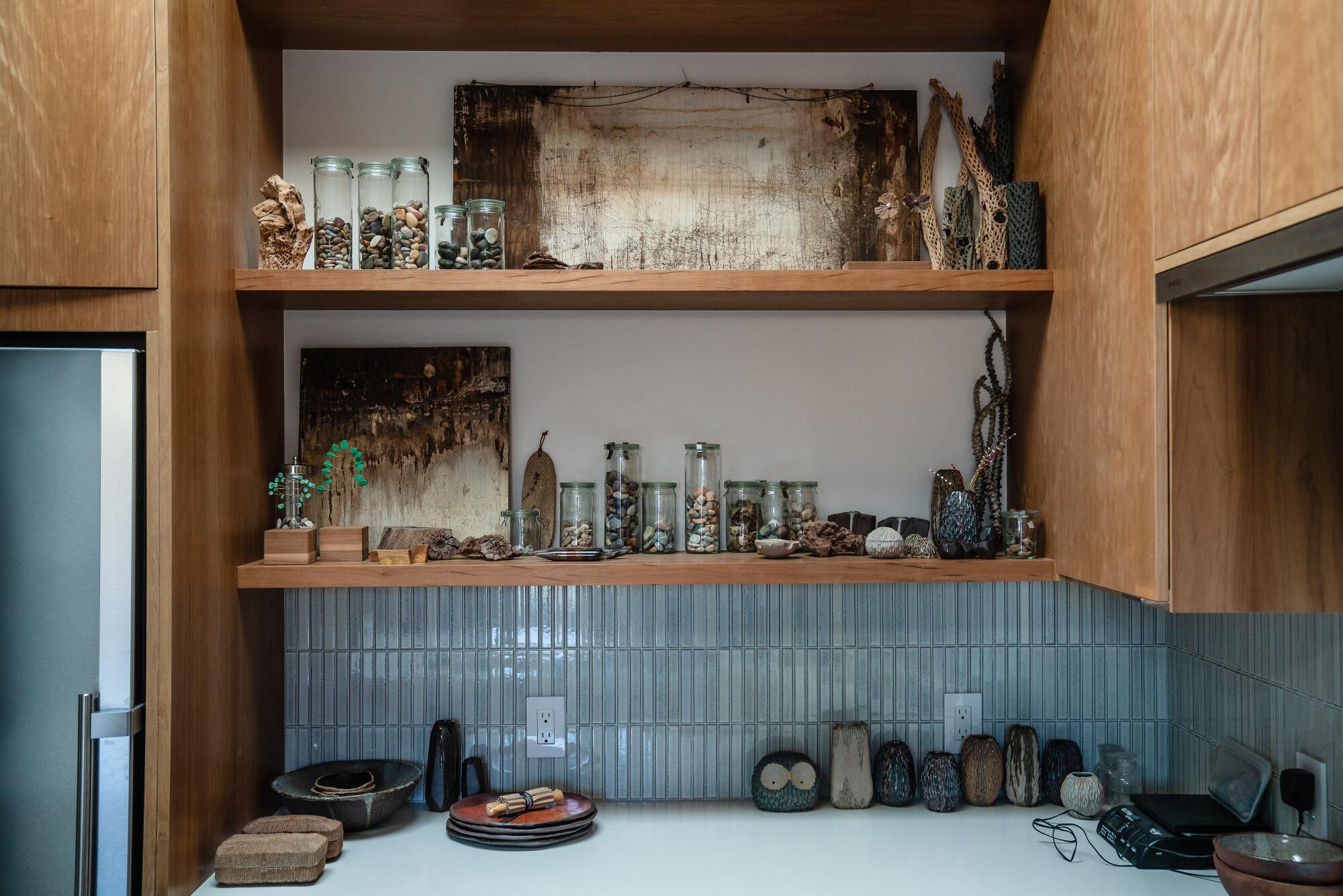 A kitchen with white counters, cherry shelves and blue ceramic tile.
