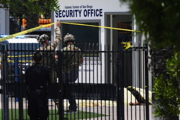 A body is covered with a tarp at the scene of a shooting outside the Islamic Center of San Diego Monday, May 18, 2026, in San Diego. (AP Photo/Gregory Bull)