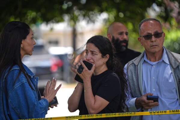 People stand behind police tape at the scene of a shooting outside the Islamic Center of San Diego Monday, May 18, 2026, in San Diego. (AP Photo/Gregory Bull)
