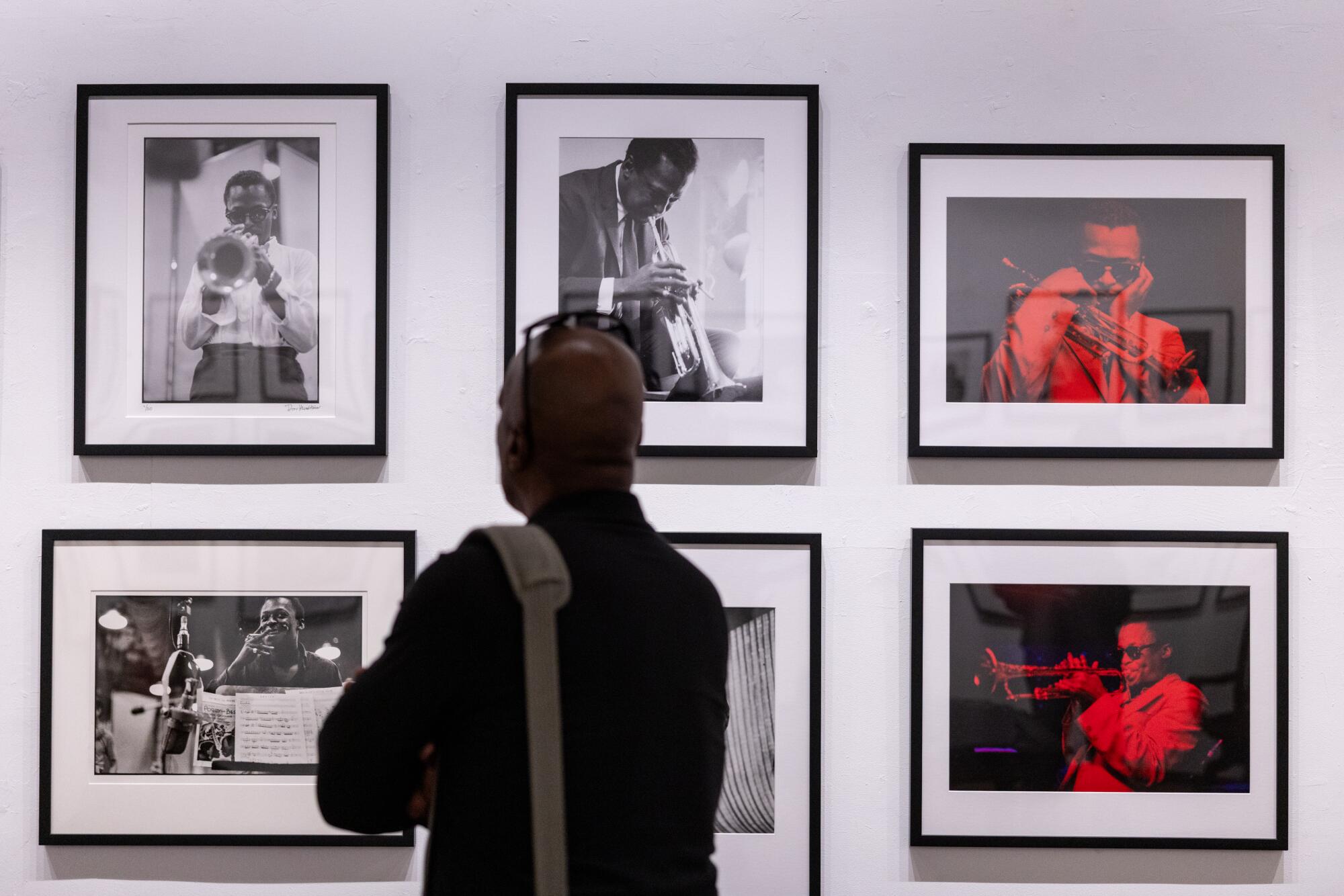 An individual dressed in a long sleeve black shirt admires photos of Miles Davis on display at Musichead Gallery.