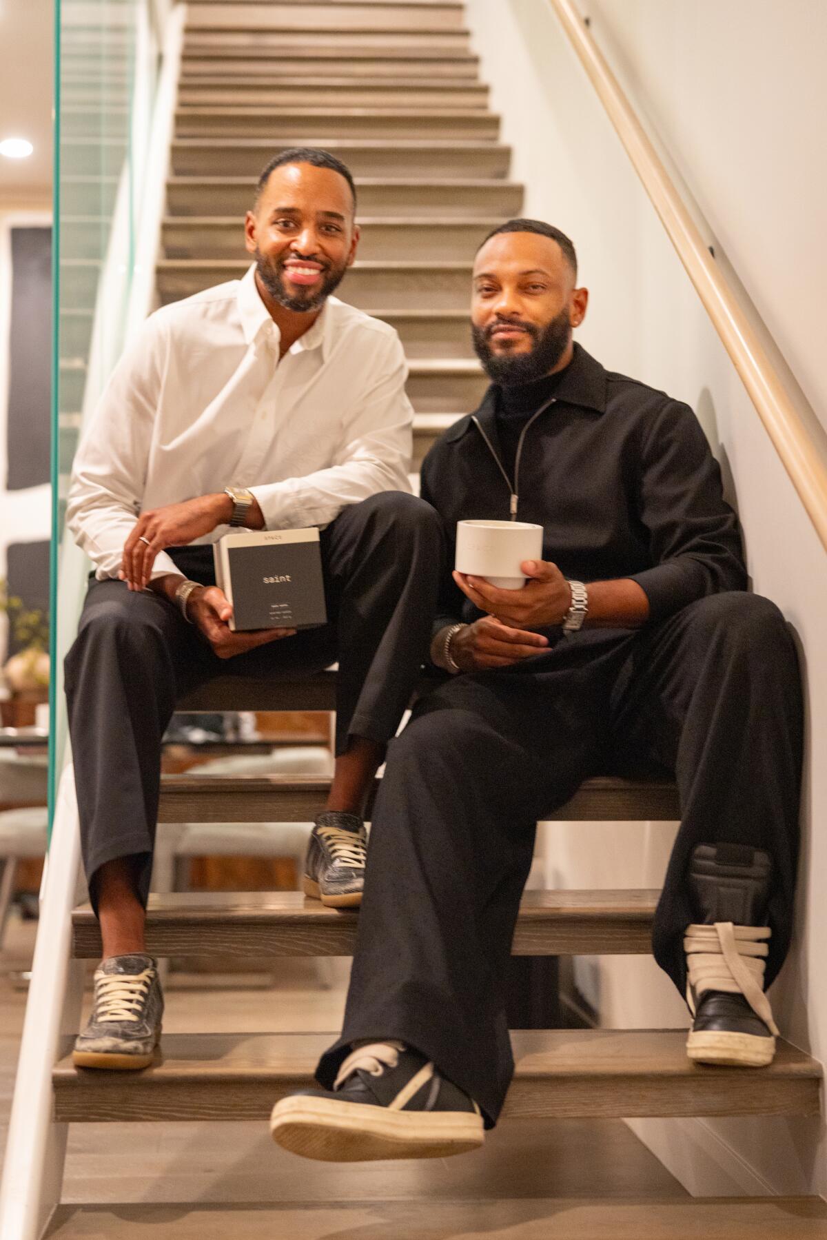 Daniel Scott, left, and Ronn Richardson seated on stairs, holding their product.
