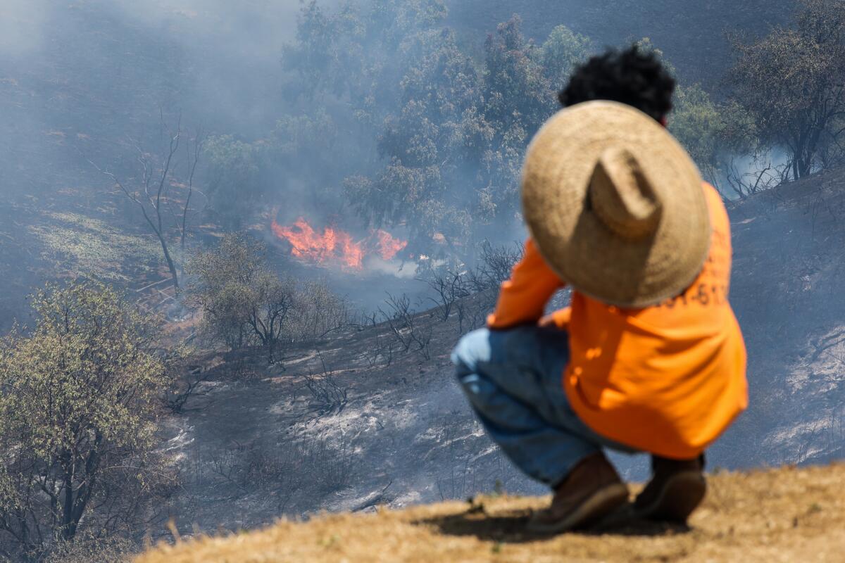 Raymond Sanchez looks over a smoldering hillside as the Sandy fire burns near Sunnyside Ave. in Simi Valley.