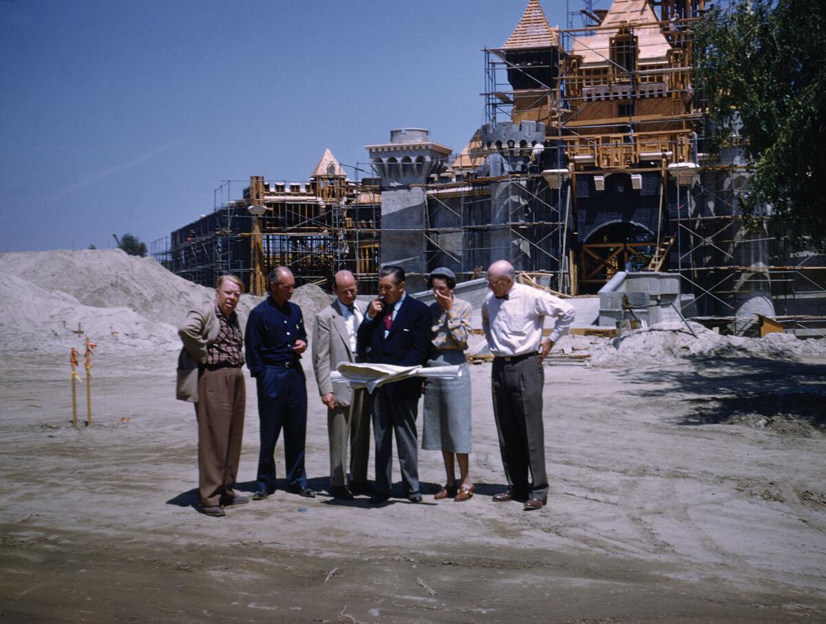 A group of people in front of a half-built Disneyland castle 