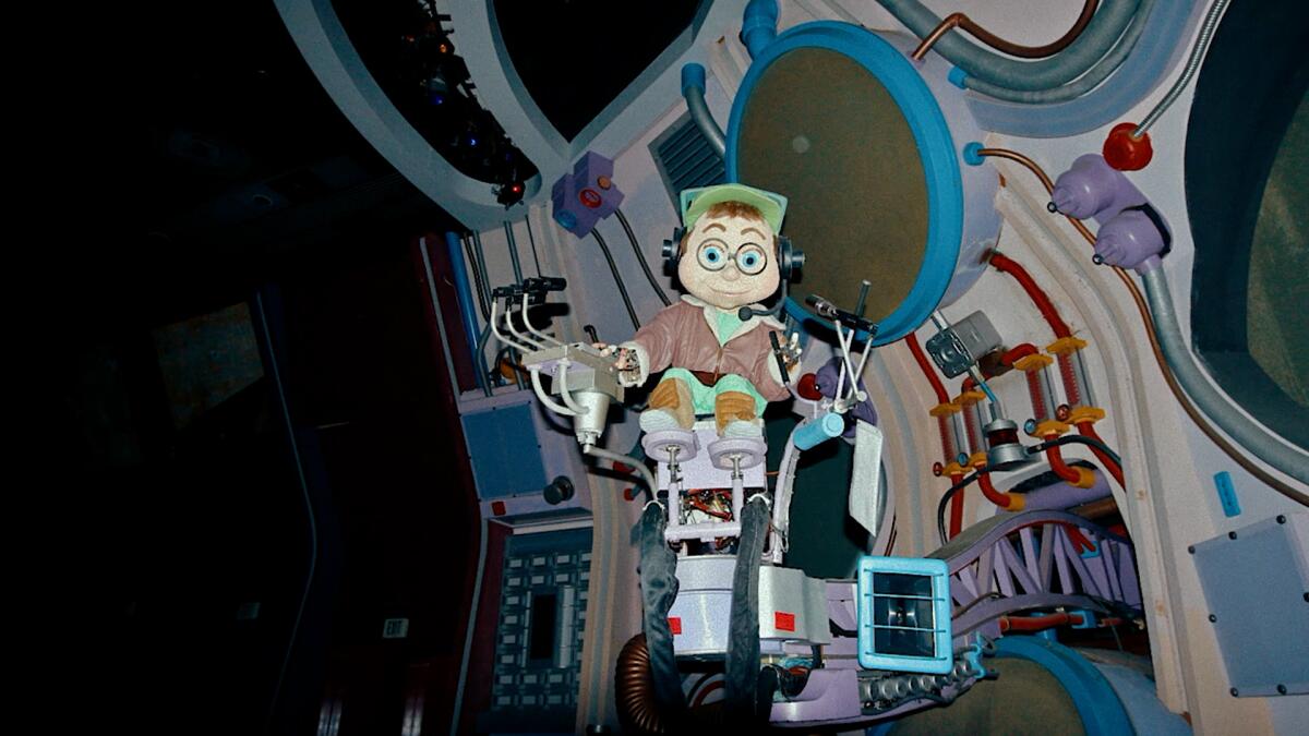 An animatronic figure with glasses and a green cap on a science contraption.