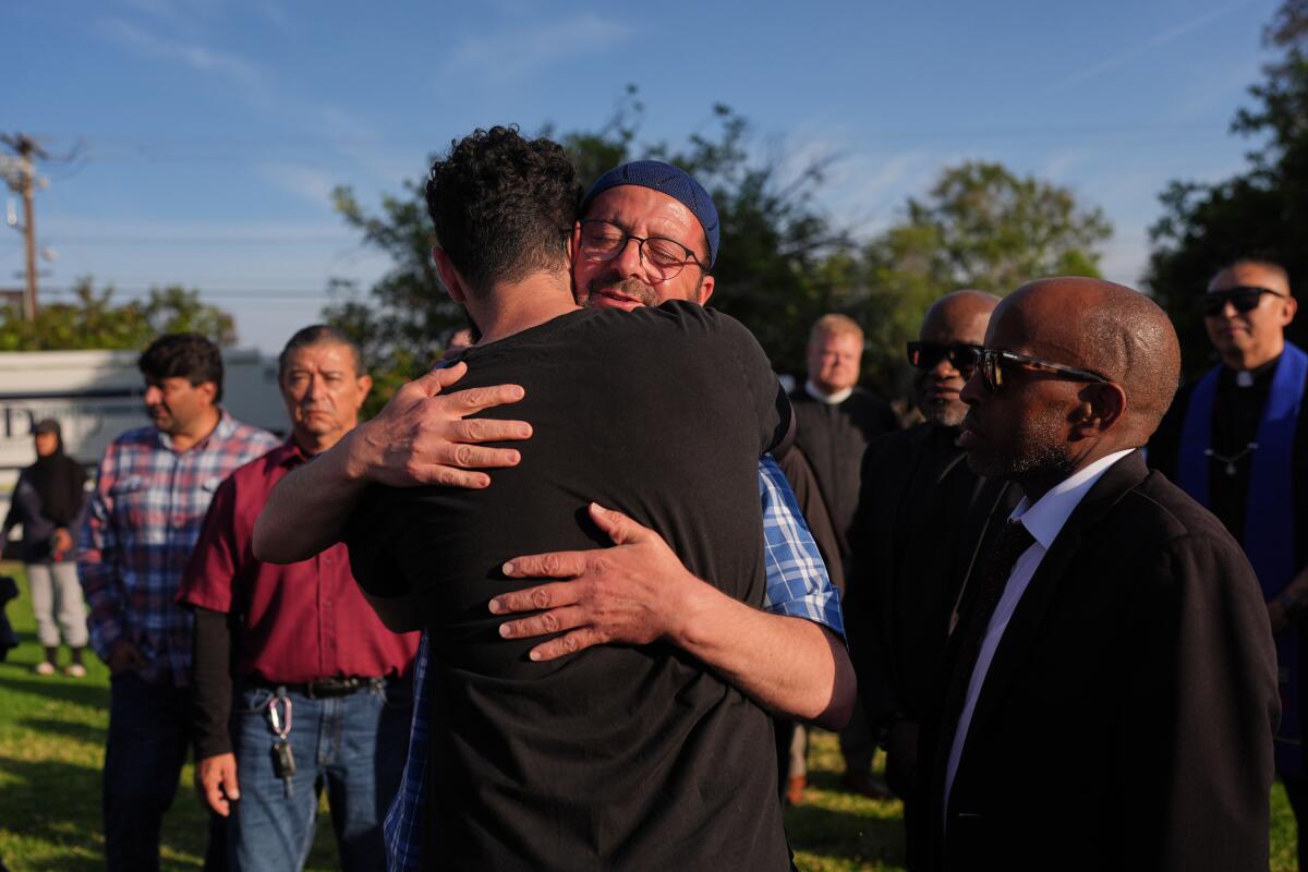 Two men embrace as other people look on 