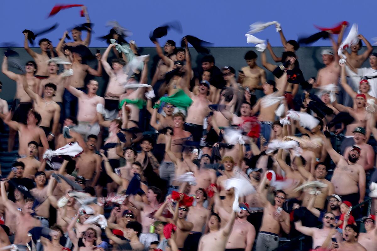 Bare chested fans wave their shirts in right field during the seventh inning of the Angels' loss to the Athletics.