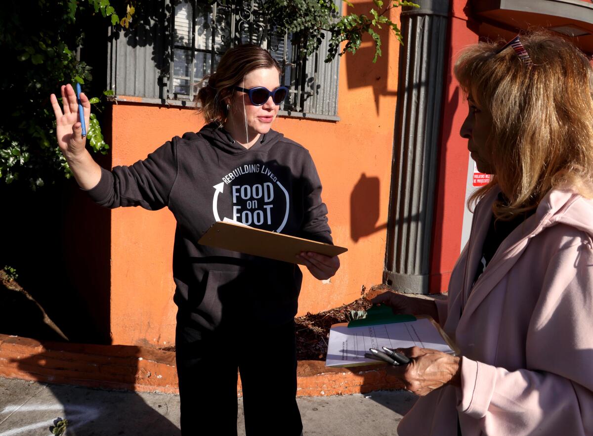 Two women talk holding clipboards.