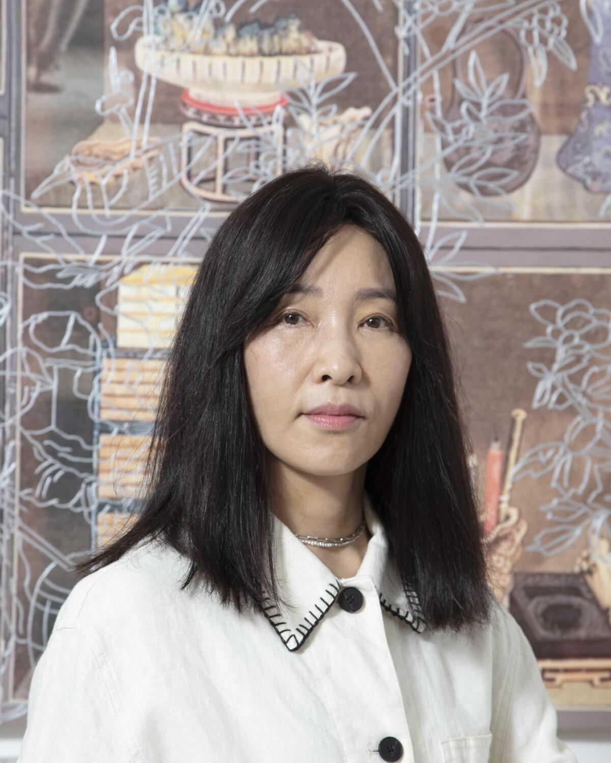 A young woman with long, dark hair wearing a white shirt poses for a portrait.