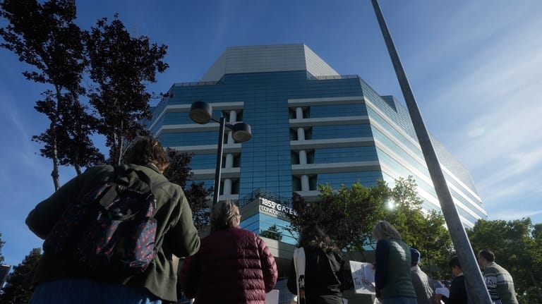 An interfaith community group holds signs while singing outside of...