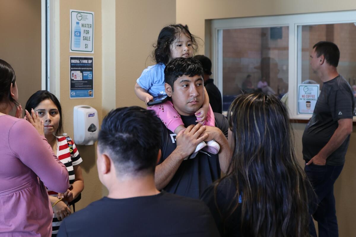 Victor Romero, of Stanton, carries his daughter, Victoria, 2, on his shoulders at the evacuation center
