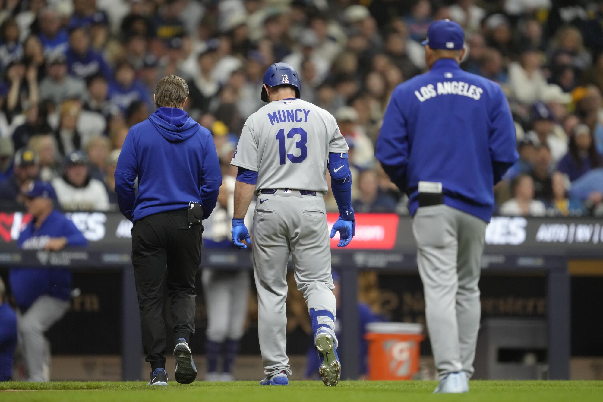 The Dodgers' Max Muncy leaves the game after being hit by a pitch during the eighth inning against the Brewers on Friday