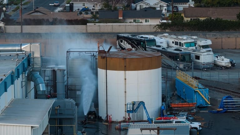 Water is sprayed on a tank that overheated at an...