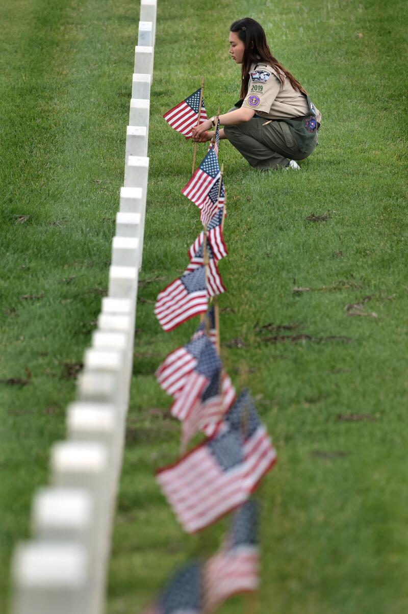 Doria Chen of Troop 2019 places a flag on a grave