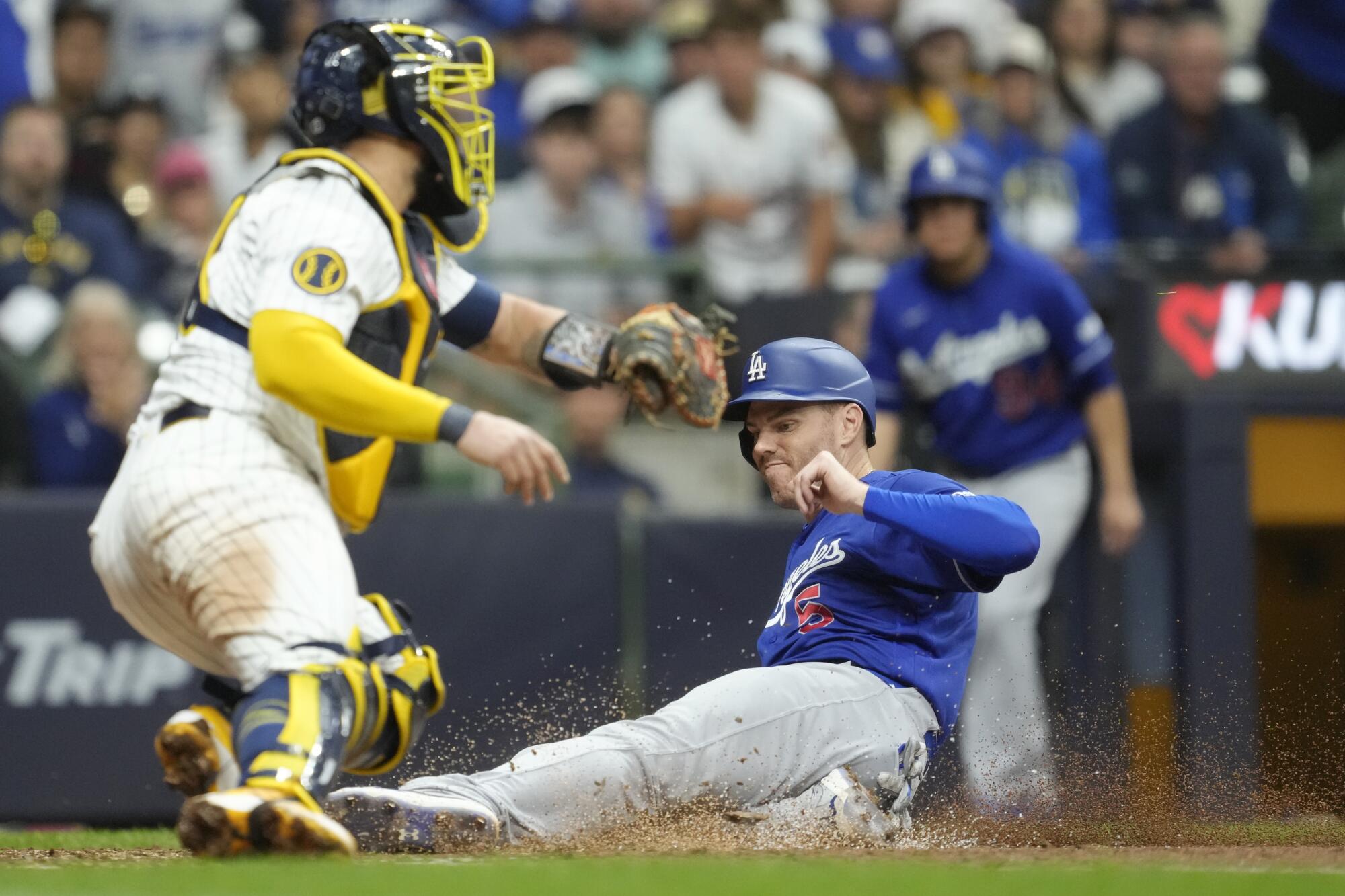 The Dodgers' Freddie Freeman slides safely past the Brewers' Gary Sánchez to score a run during the eighth inning.