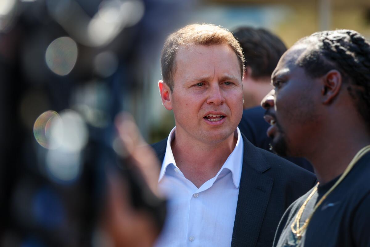 A man in a suit speaking to another man