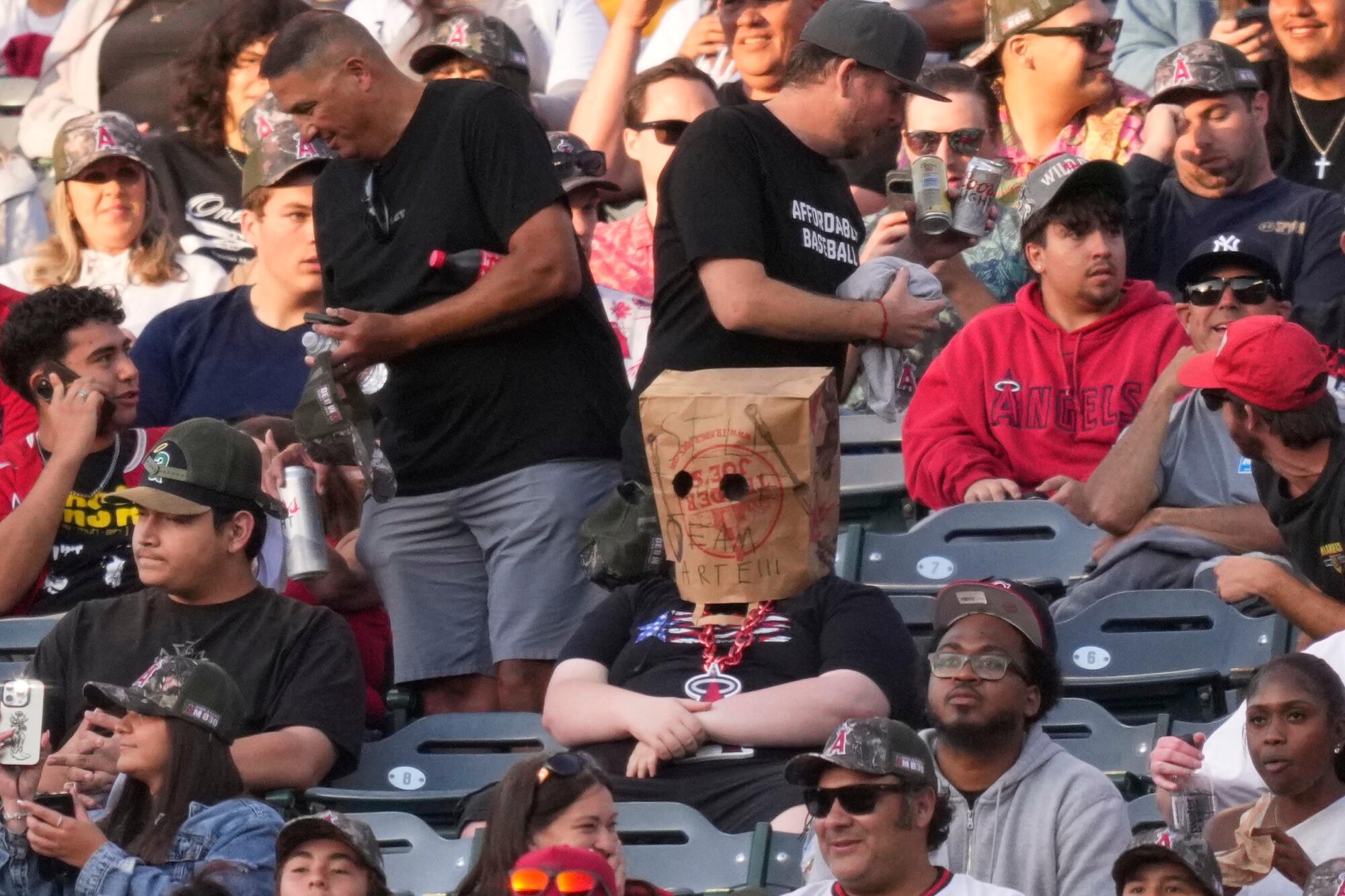 A fan wears a bag over his head that says "Sell the Team Arte!!!" during a game against the Rangers  on Friday.