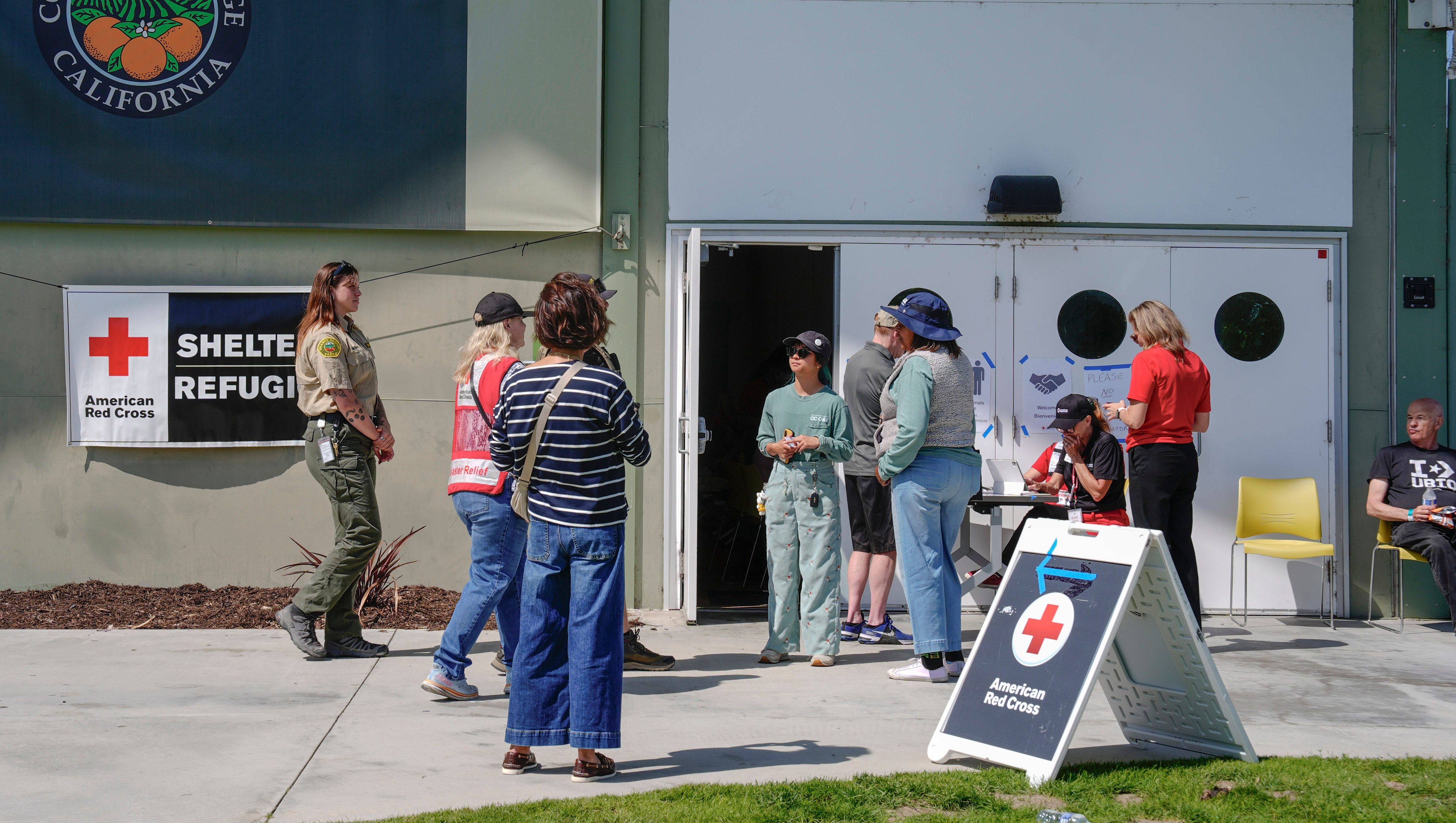 Red Cross workers and other emergency personnel serve evacuees as they look for food or a place to stay outside Freedom Hall in Fountain Valley while awaiting clearance to return to the homes in Garden Grove and nearby communities in California, May 23, 2026.