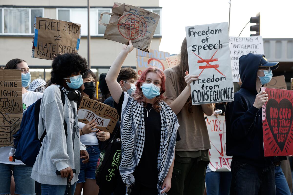 A group of protesters amid signs that read “Free speech ≠ hate speech.” “