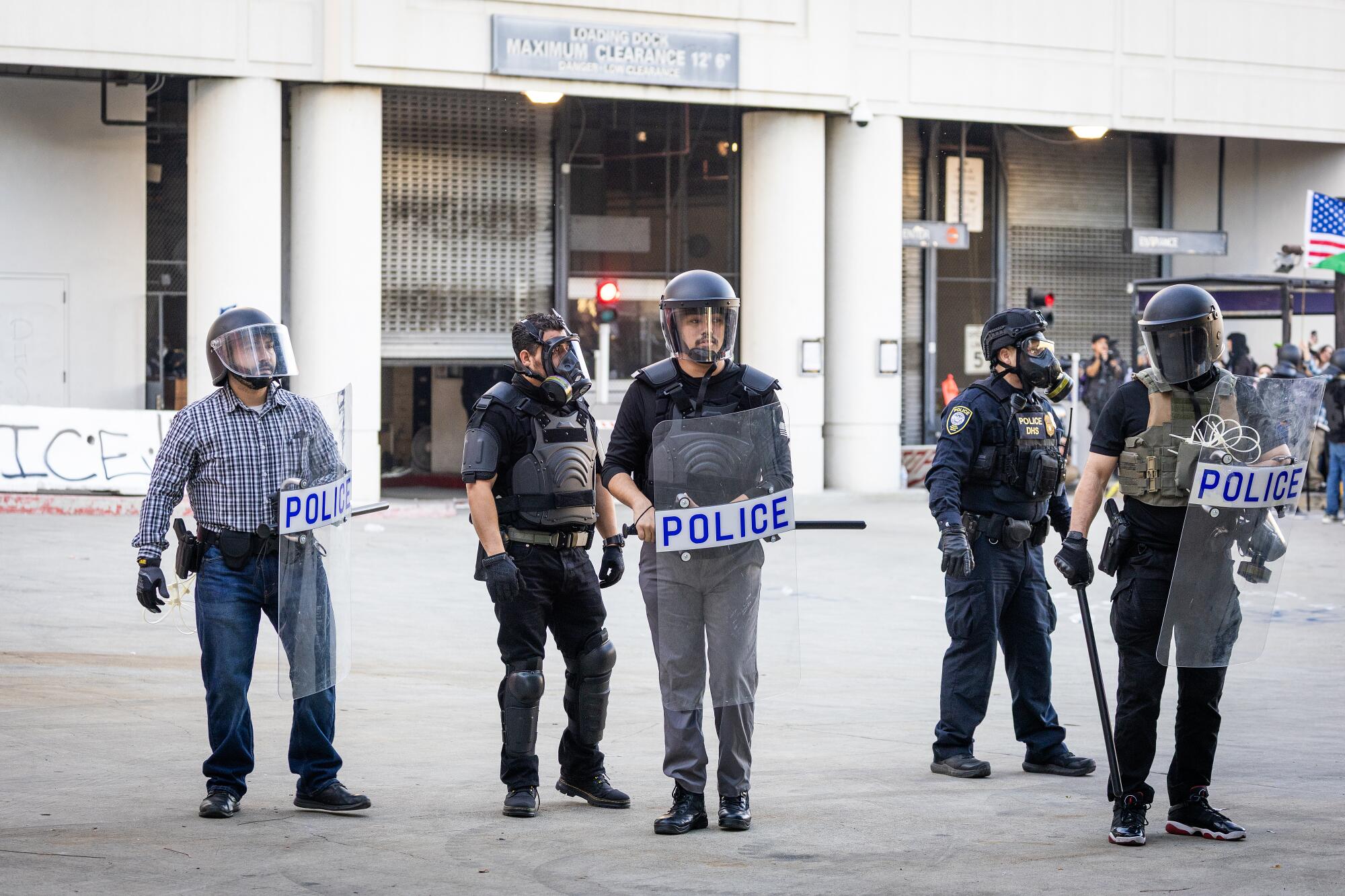 Federal agents, some wearing street clothes and some wearing uniforms and protective gear, stand together.