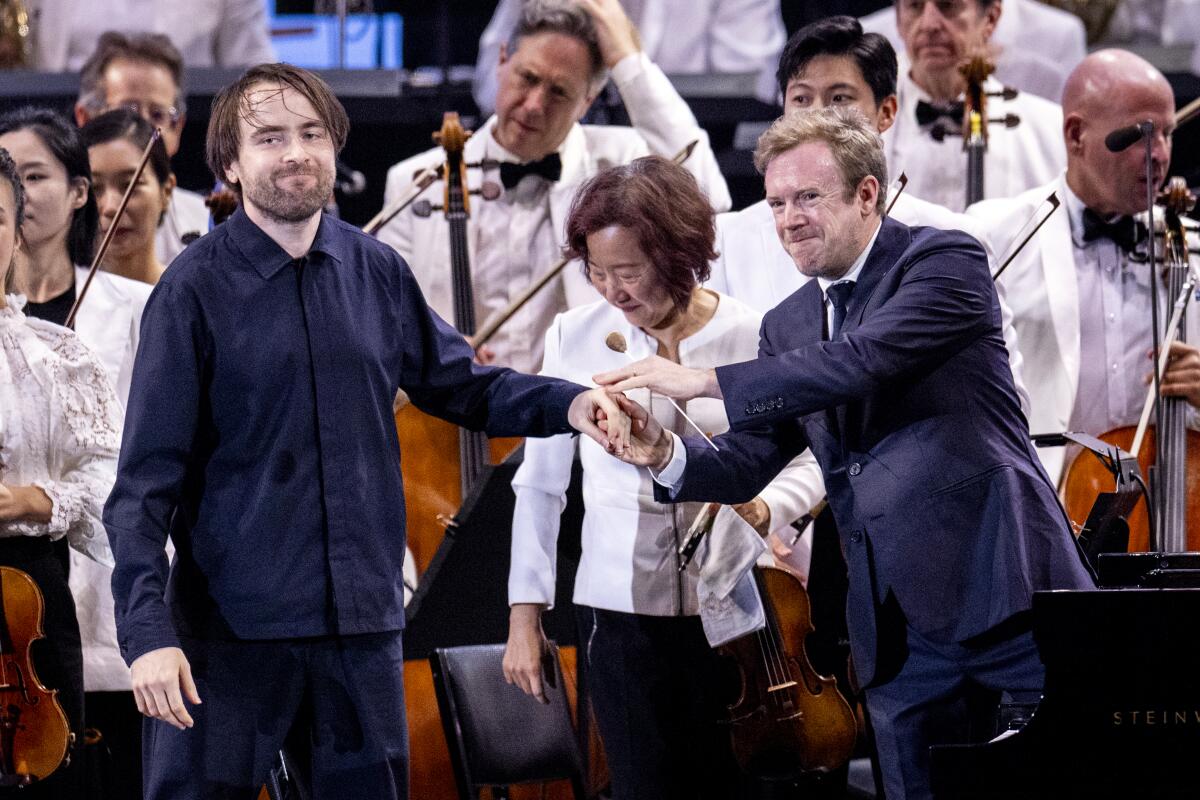 Two men on stage with an orchestra.