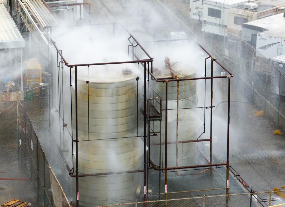 An aerial photo of water being sprayed on large storage tanks at the GKN Aerospace facility in Garden Grove on Sunday.