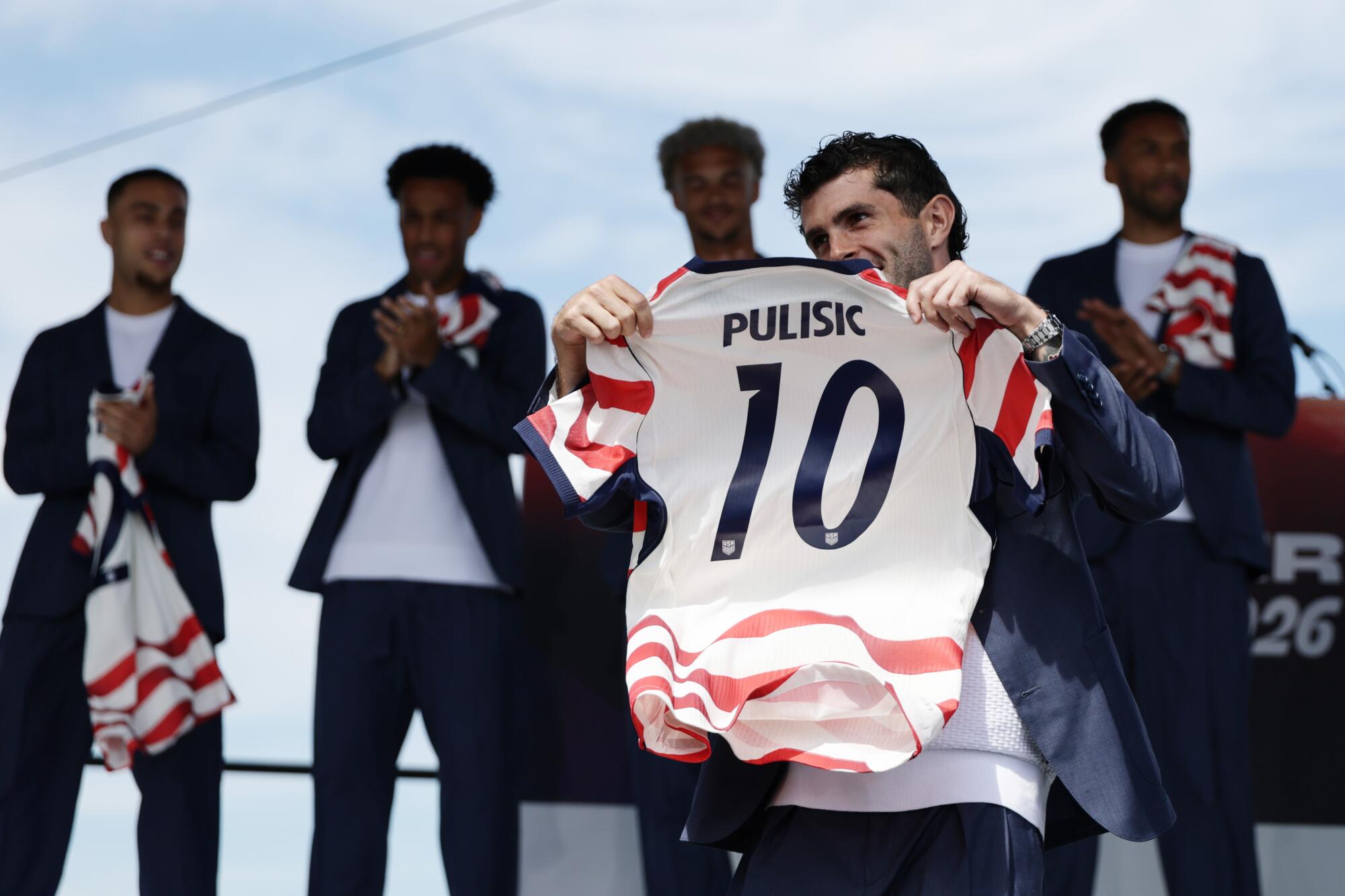 Christian Pulisic holds up his U.S. jersey during a rally Tuesday in New York.