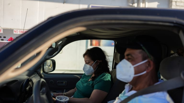 Two evacuees sit in their pickup truck at a gas...