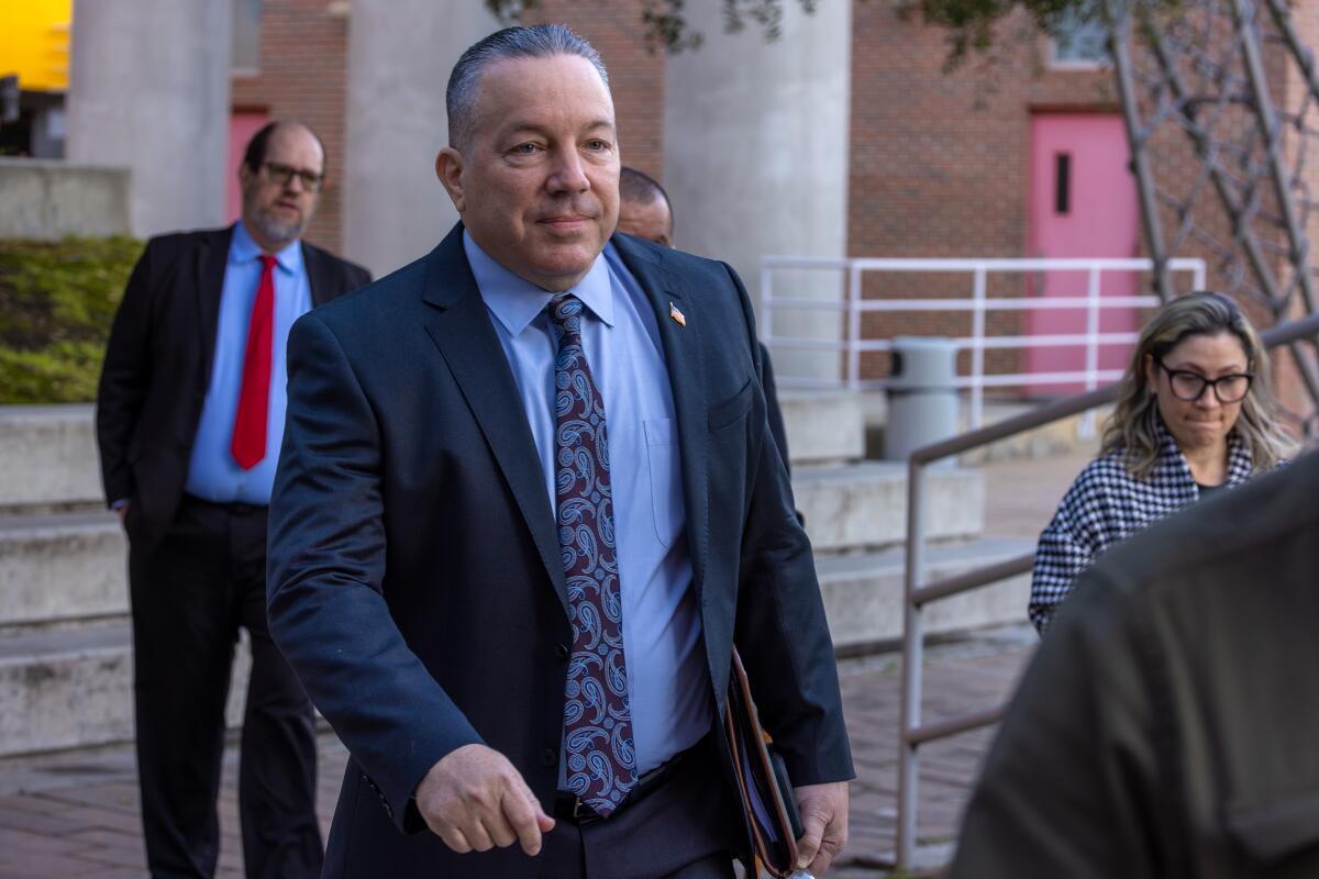 A man in a suit and tie walks with others.