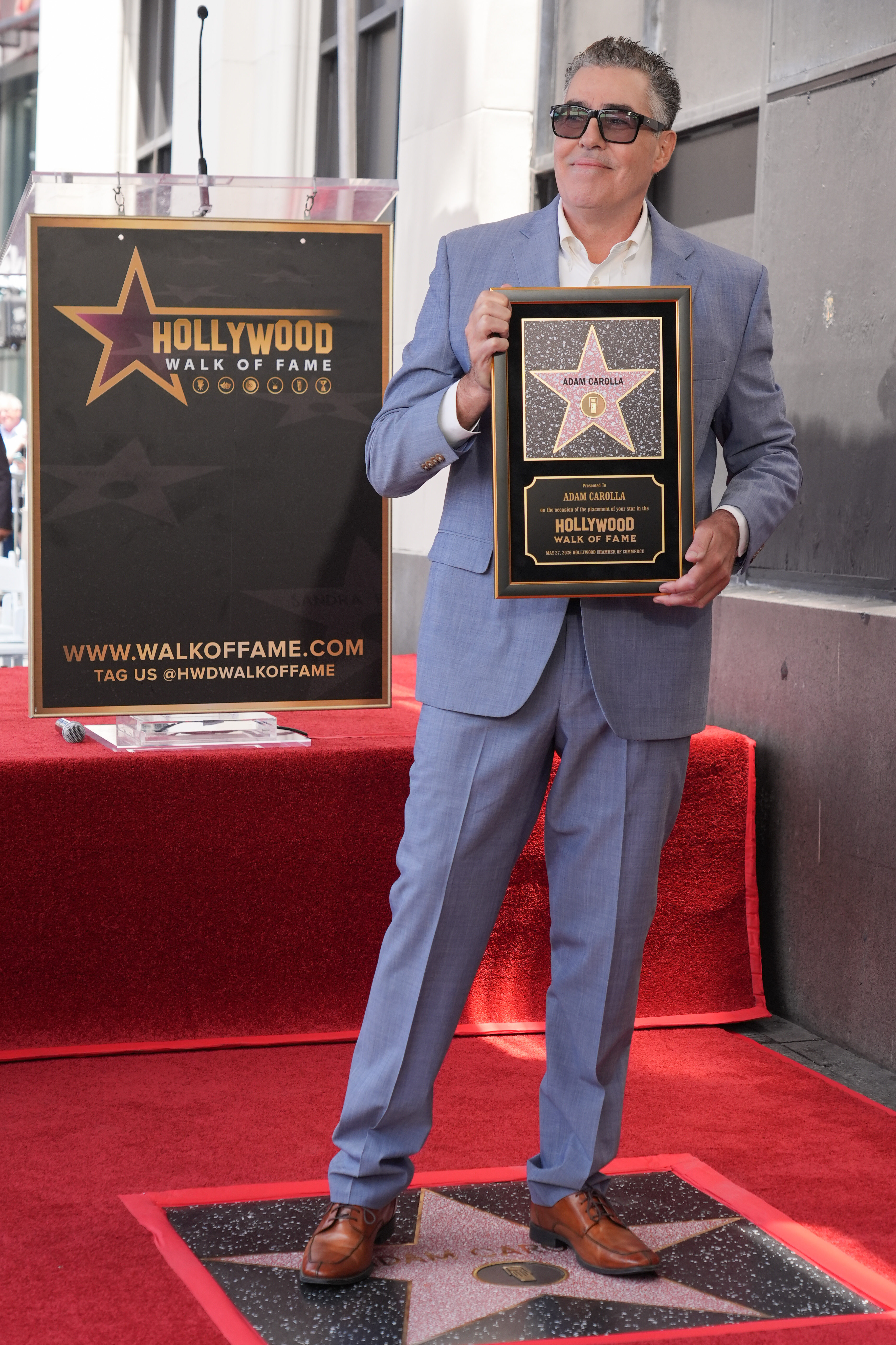 Adam Carolla poses with his new star during a ceremony...