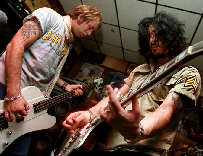 Two men playing guitar face eachother.