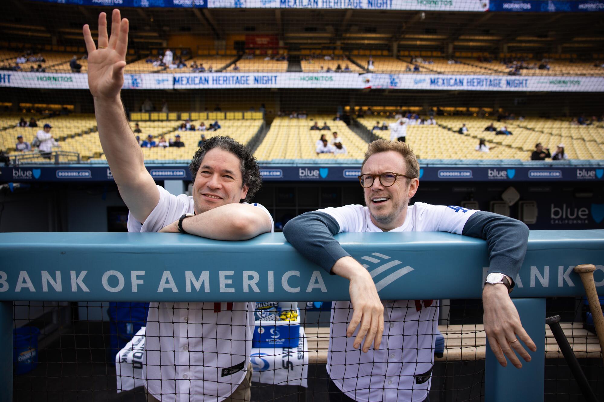 Gustavo Dudamel, left, and Daniel Harding stand in the dugout before a Rockies vs. Dodgers game at Dodger Stadium.