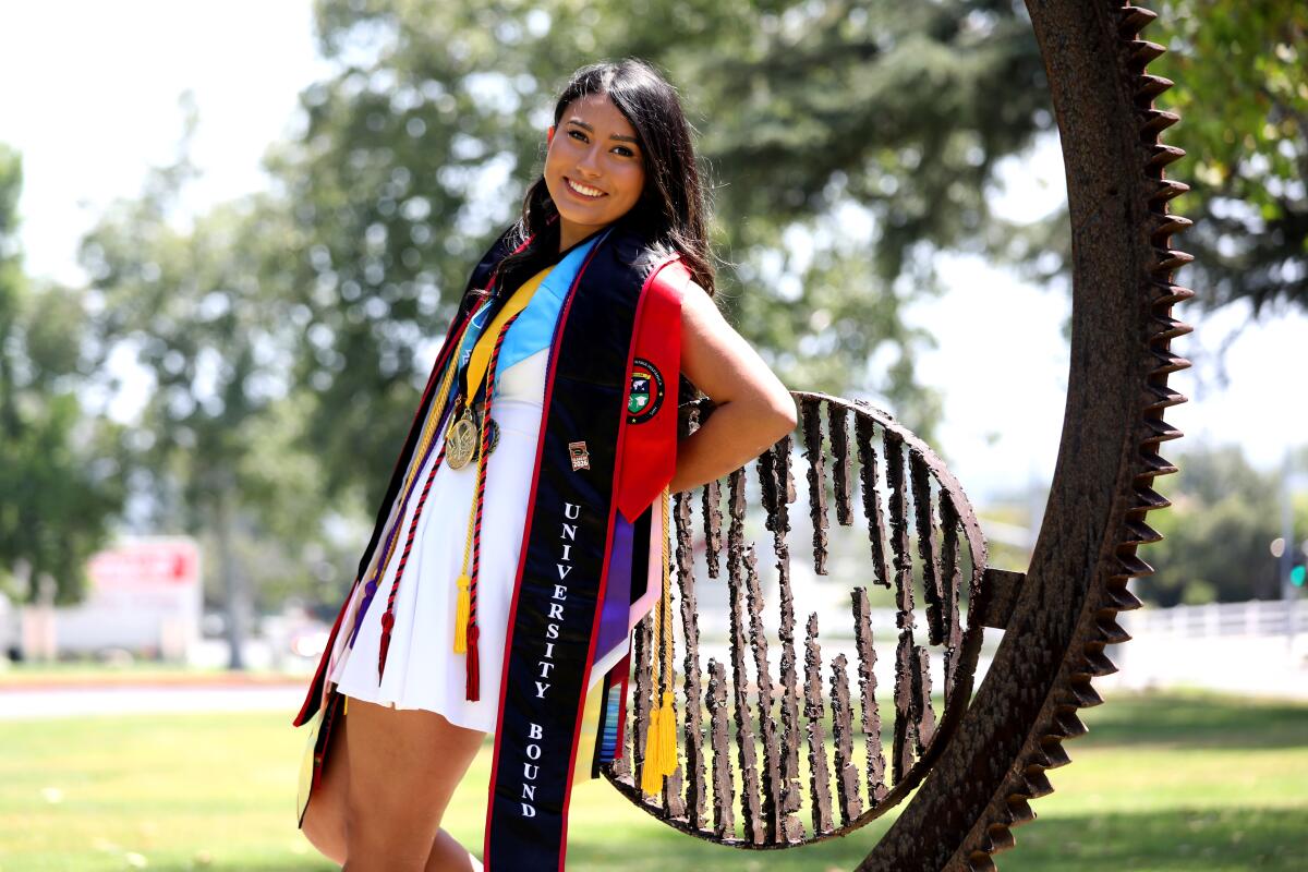A teen poses for a portrait wearing graduation stoles 
