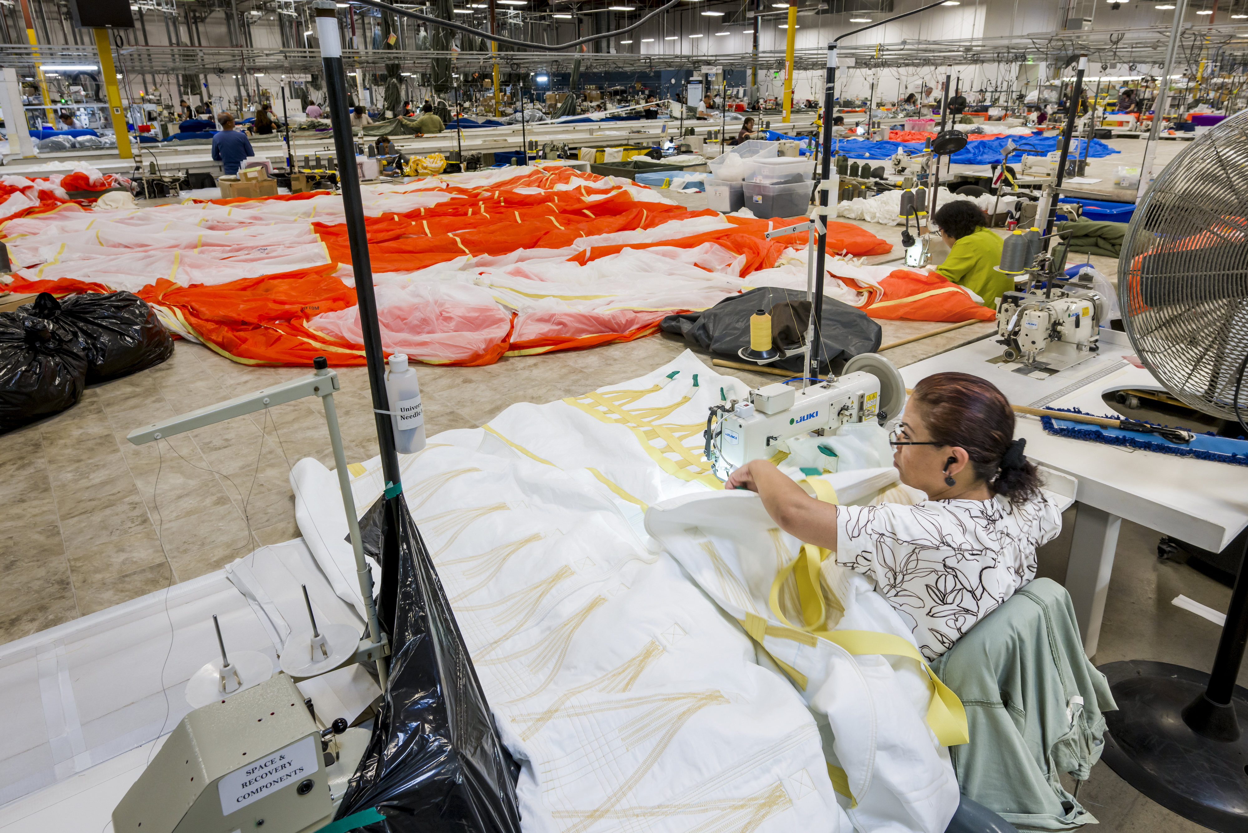A sewing machine operator works on one of three parachutes...
