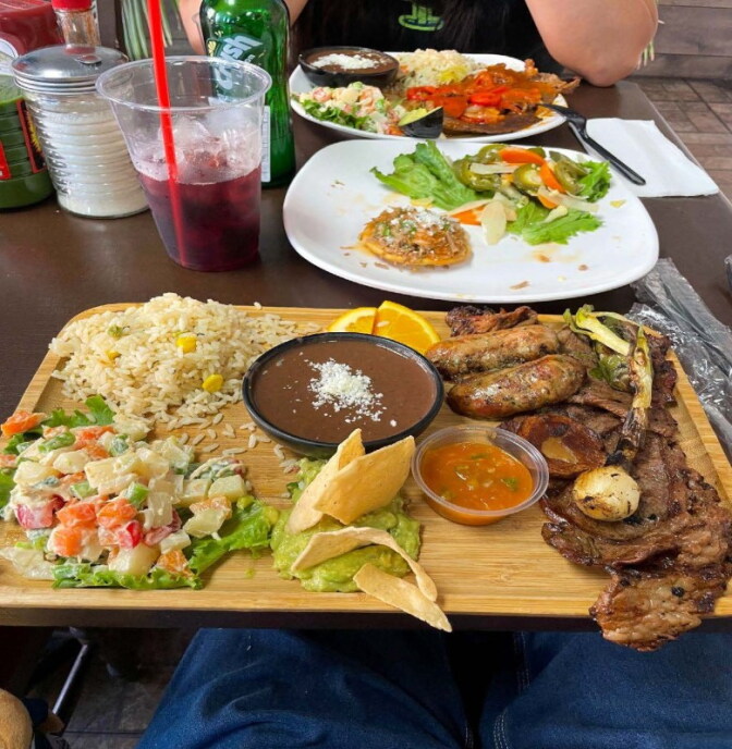 A plate with beans, rice, a salad, grilled meats and chips.