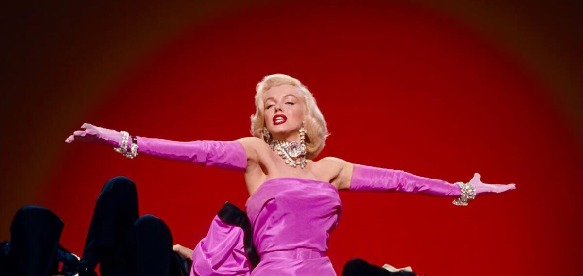 A woman in a pink dress sings about diamonds.