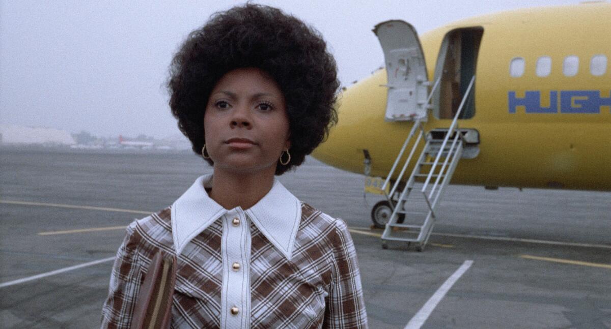 A woman with an Afro deplanes.