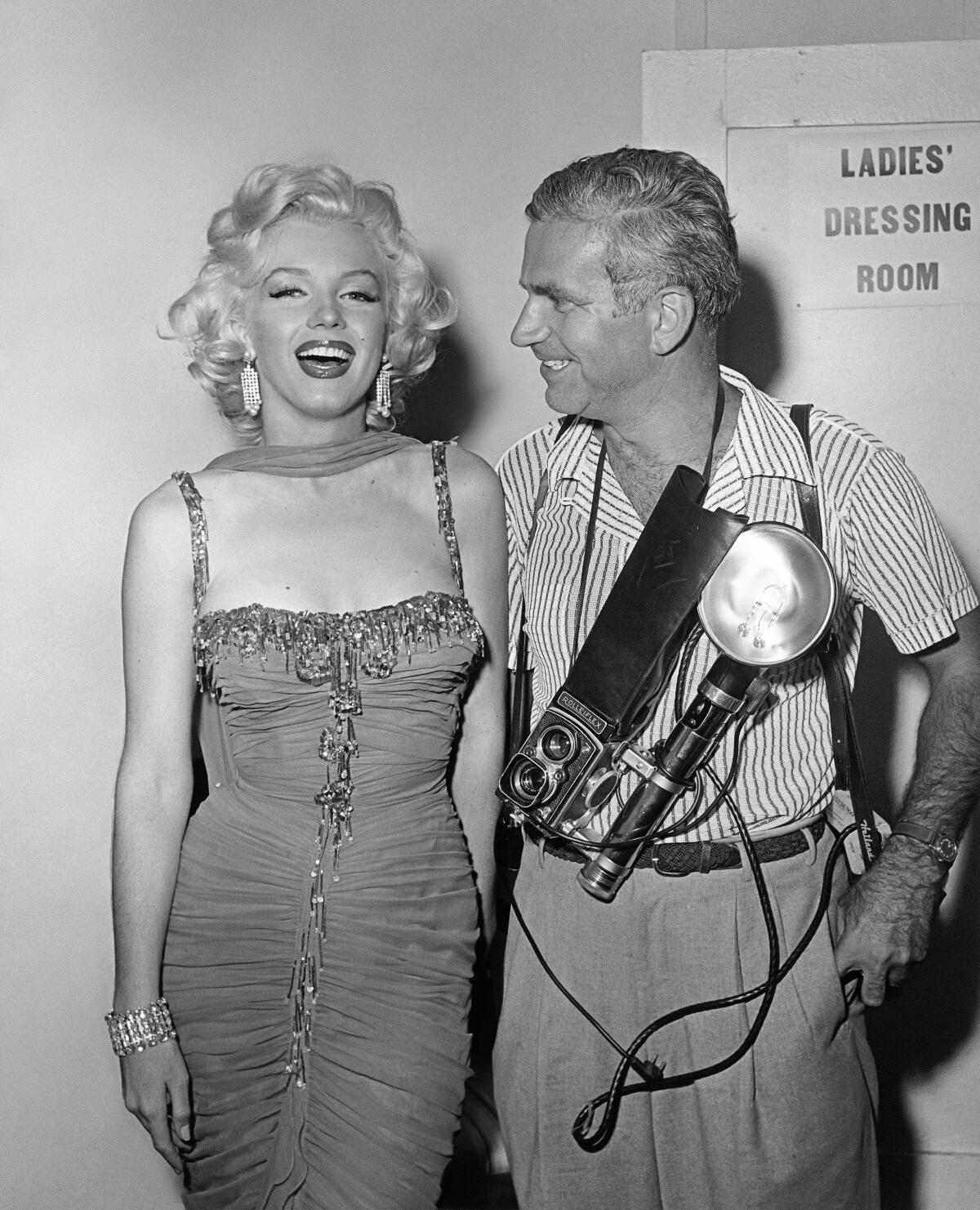 A woman in a low-cut dress stands with a photographer.
