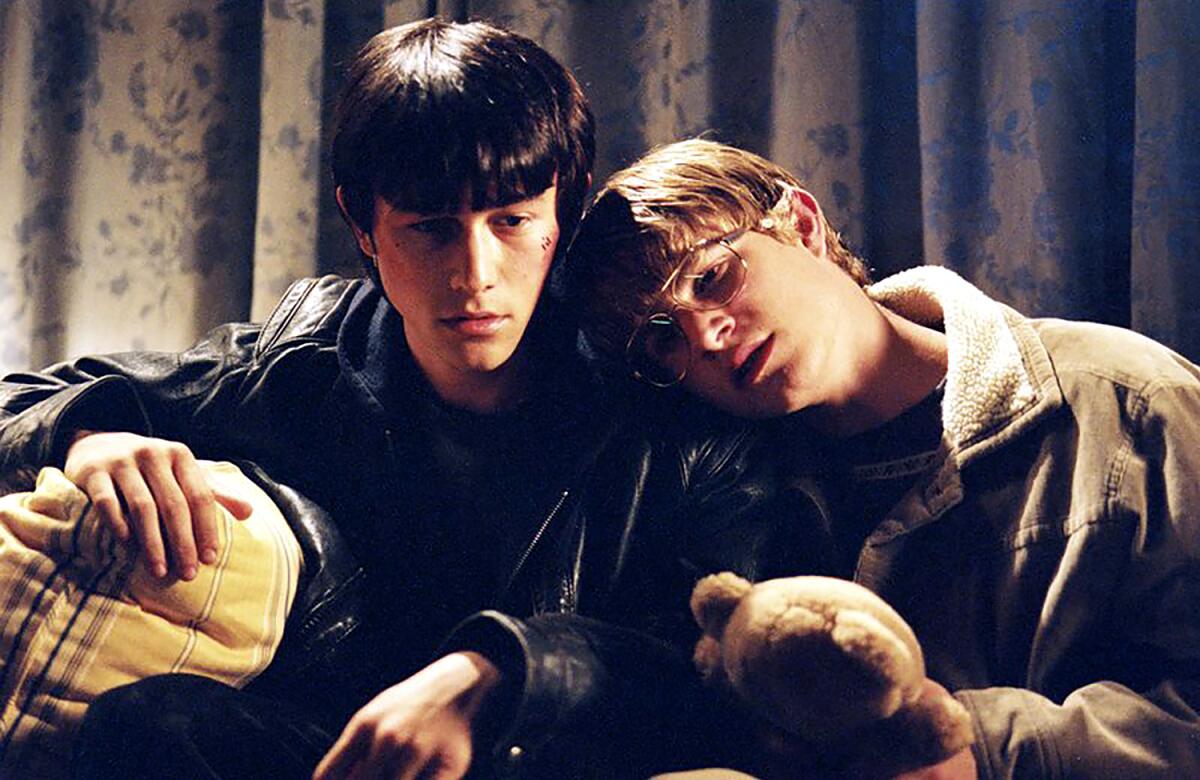 Two young men sit on a couch together.