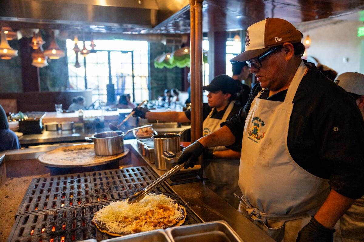 Alfonso "Poncho" Martinez of Lugya'h cooks a tlayuda over the open fire grill at Maydan Market.