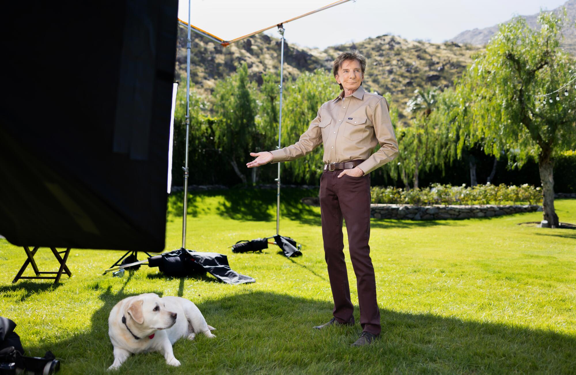 Barry Manilow stands outside beside his dog. 