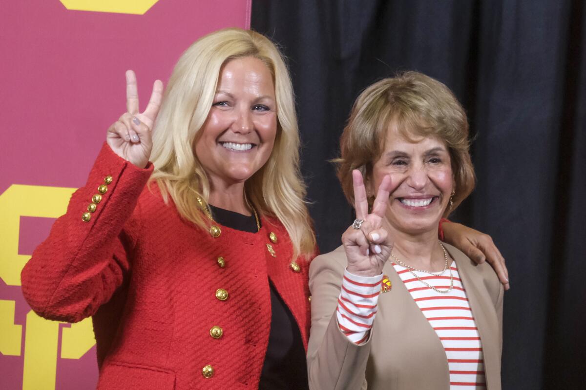 USC athletic director Jennifer Cohen, left, and university president Carol Folt, right, flash the "V for Victory" hand sign.