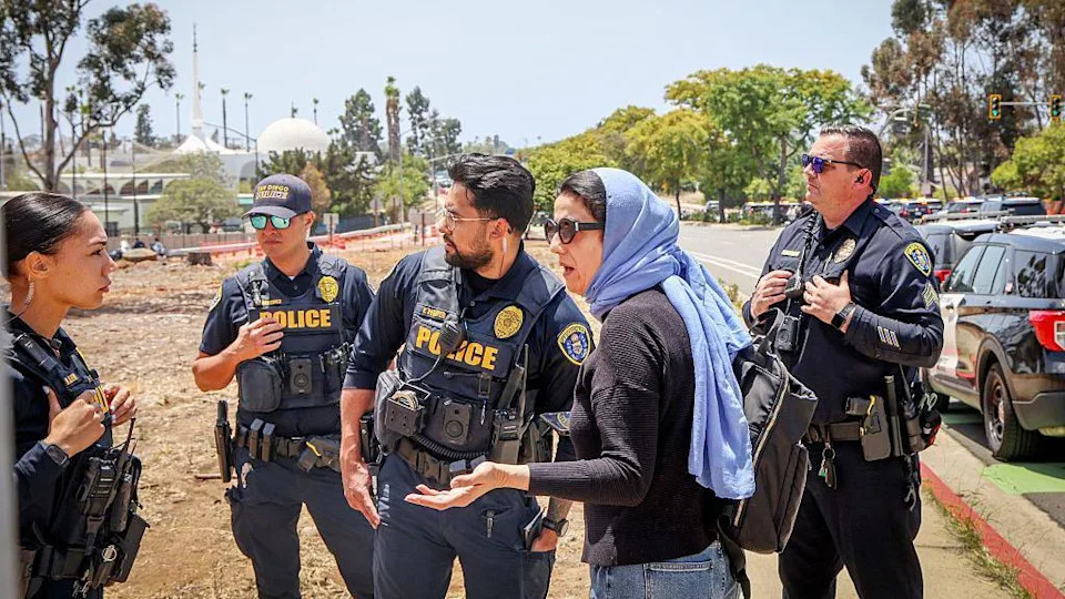 A woman in headscarf speaks to police near the mosque