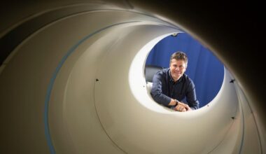 Simon Cherry framed inside the open end of a large white pipe, a PET scanner