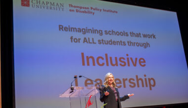 Kari Adams speaks onstage at the 2025 Thompson Policy Institute Summit on Disability and Inclusion at Chapman University, standing in front of a presentation screen displaying the words “Inclusive Leadership.”