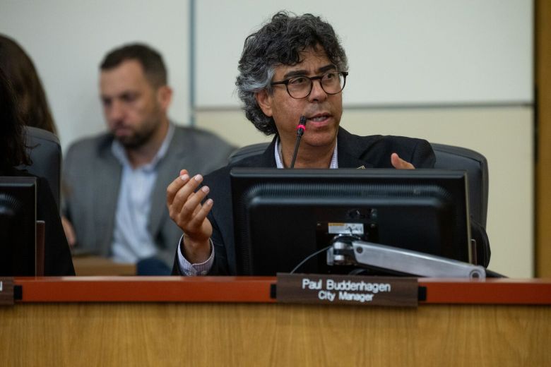 A man gestures as he speaks into a microphone