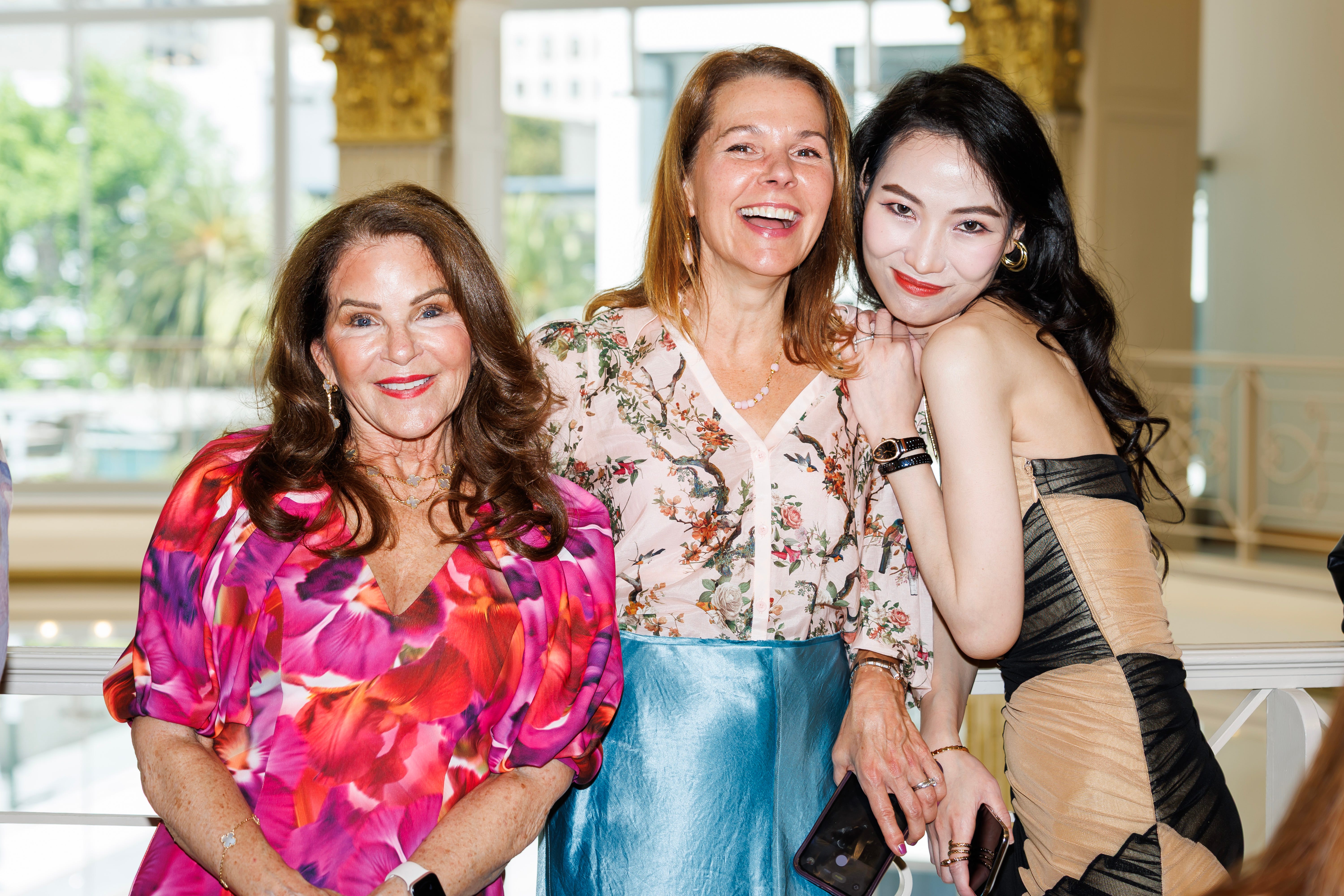 Three women posing together indoors.