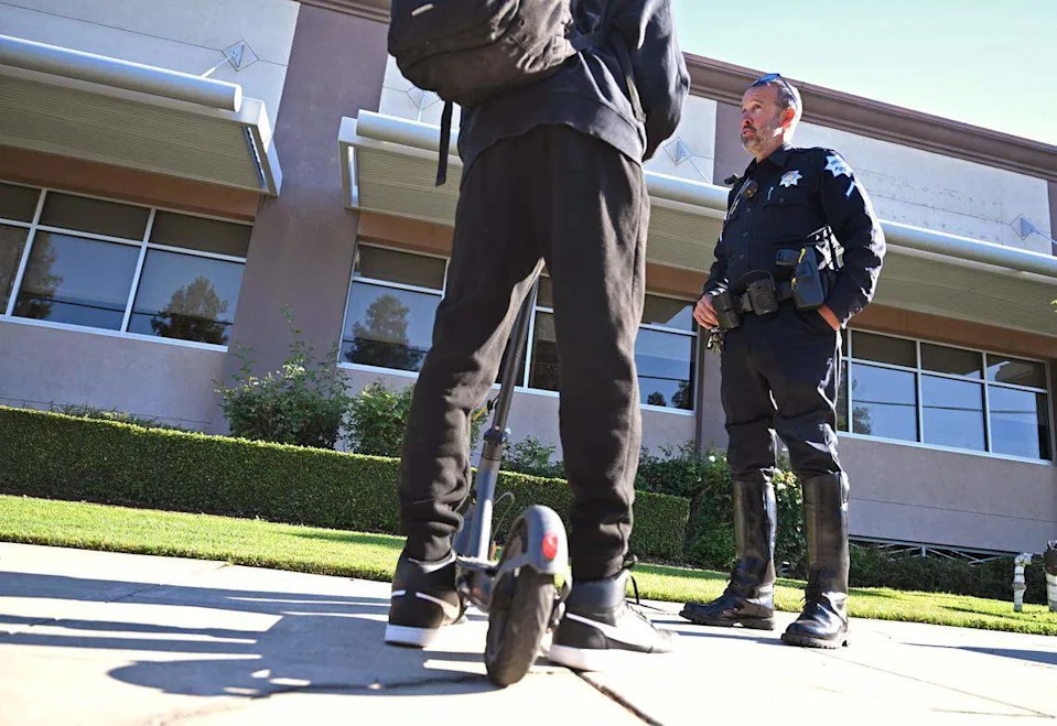 Fresno Police traffic officer Jason Hurley addresses a Clovis West student with the law regarding riding e-scooters on sidewalks Thursday morning, May 21, 2026 in Clovis.