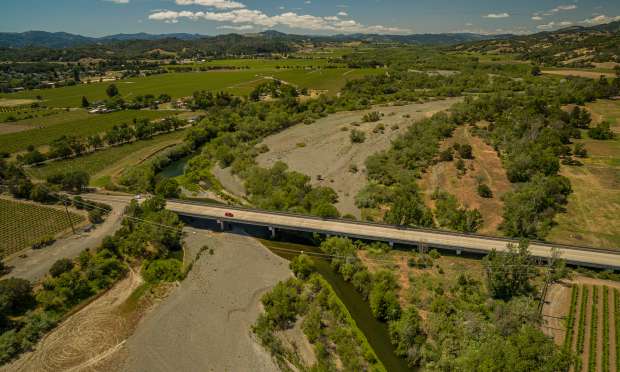 The Russian River snakes underneath the Geyserville bridge at Highway 128 in an ever growing dry riverbed in May 2022. (Chad Surmick/The Press Democrat file)