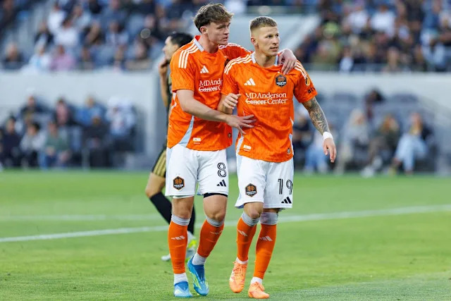 Mateusz Bogusz #19 of Houston Dynamo FC celebrates with Jack McGlynn #8 after scoring a goal during an MLS match against LAFC on May 10, 2026 at BMO Stadium in Los Angeles, California.