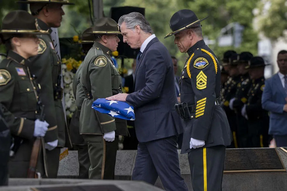 Gov. Gavin Newsom places the American flag on the monument to fallen officers during the annual California Peace Officers’ Memorial enrollment ceremony in Sacramento on Monday.